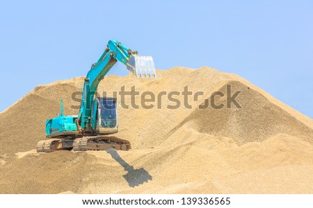 blue excavator extening its bucket at sandpit