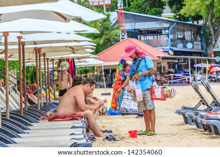 PATTAYA, THAILAND - MAY 25: Local merchant selling souvenirs to tourists at Pattaya beach on May 25, 13, it is a city in Thailand, a beach resort popular with tourists and expatriates