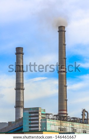the white smoking from chimneys of a factory against a blue sky.