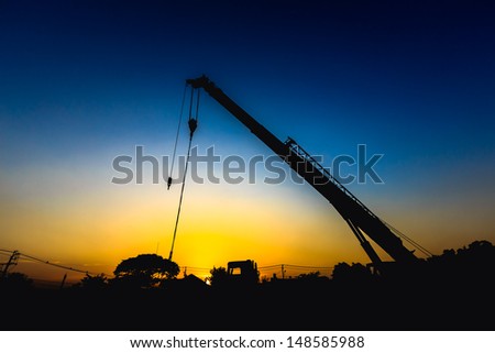 mobile crane operating, silhouettes at sunset