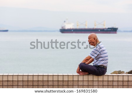 PENANG, MALAYSIA-DECEMBER 20: Unidentified old Chinese man sit by Penang beach on Dec 20, 13 at Penang, Malaysia. Penang is a state in Malaysia located on the northwest coast of Peninsular Malaysia.
