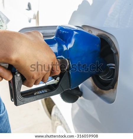 blue gasoline pump nozzles filling in the tank with hand