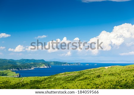 Russian resort area of the Sea of Japan with hills, clouds, rocks and greenery in sunny day