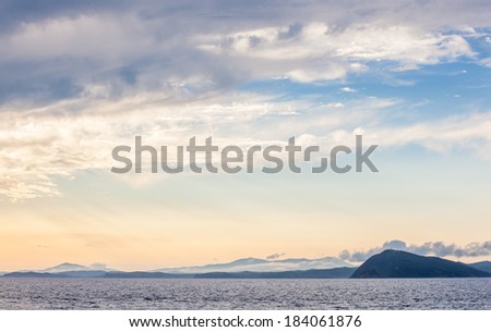 hills and mountains in the evening sun near the water sea bay at sunset in the clouds haze
