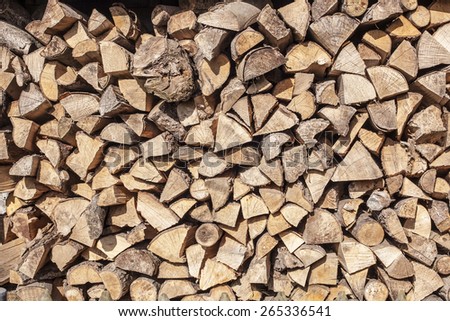 firewood stacked in a woodpile in the courtyard, lit by sunlight