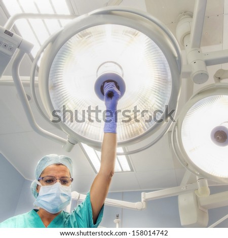 nurse places a surgical lamp on the operating table