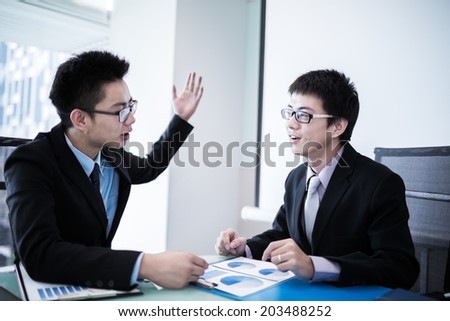 Two Businessmen Having Informal Meeting In Modern Office.Asian