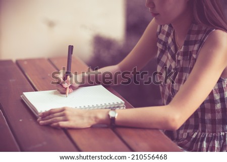 Close-up of a young girl writing into her diary, in the park