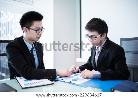 Two Businessmen Having Informal Meeting In Modern Office.Asian