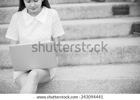 Young woman using laptop on steps outdoors