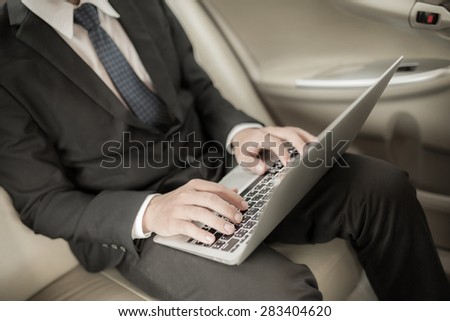 Young business using laptop in back seat of car
