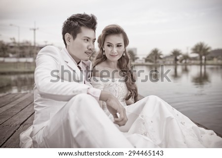 Bride and groom sitting on the edge of the river bridge