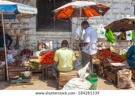 STONE TOWN, ZANZIBAR/TANZANIA - APRIL 4 2012: Old Town Market under bright sun with sellers and buyers. This is a classic Swahili public space, mixing architectural and cultural influences.