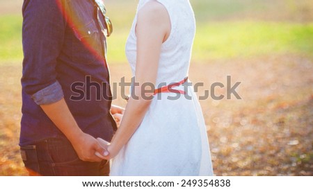 Young couple in love walking in the autumn park holding hands in the sunset