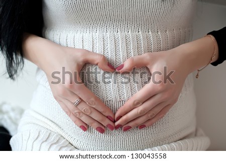 Pregnant girl hugging hands tummy. Hand of a woman hugging belly