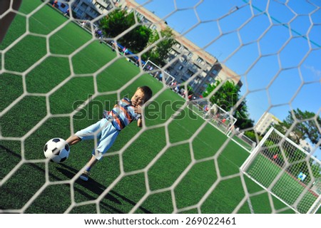 little boy playing football on football pitch