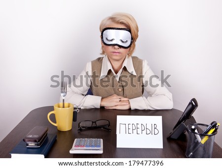 Tired working girl in a sling eyes sleeps on the desktop labelled \