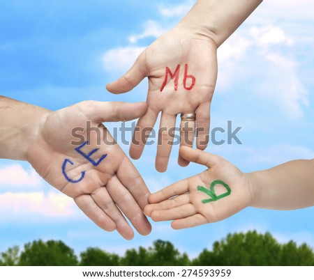 The word family written in colorful Russian letters on the palms of the father, mother and child, on a background of blue sky and greenery