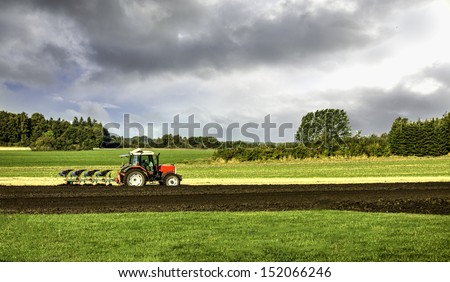 Small scale farming with tractor and plow in field