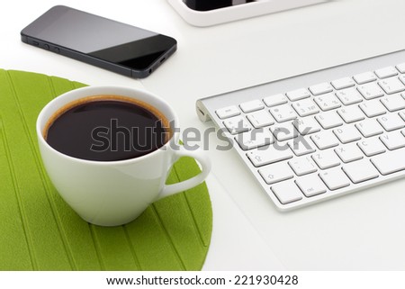Coffee mug on the table with a phone and keyboard