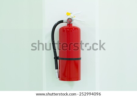 Fire extinguisher on white wall.