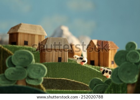 Countryside with farms, meadows, cows and mountains - stylized nature background made of wool