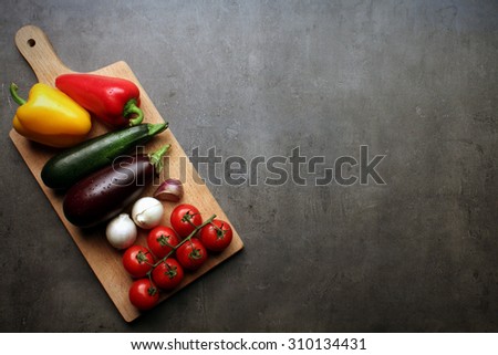 Fresh vegetable on wooden cutting board with space for your recipe text on grey kitchen countertop