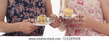 close up of two children with fairy cakes on plates, isolated on white background