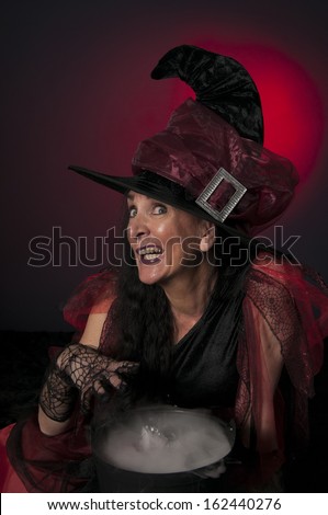 Halloween witch with cauldron, casting spells on dark background