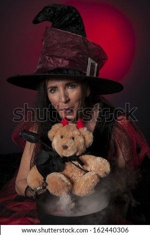 Halloween witch with cauldron and vampire teddy bear, casting spells on dark background