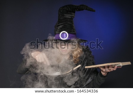 pretty woman dressed as Halloween witch casting spells isolated on dark blue background