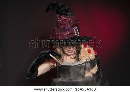 pretty Halloween witch with cauldron isolated on dark red background