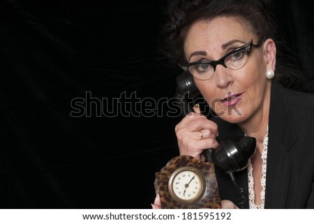 Vintage 1940\'s style woman in office situation, worried about the time, and angry on the telephone, isolated on black background