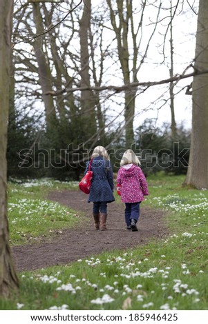 pretty children walking in woods of snowdrops