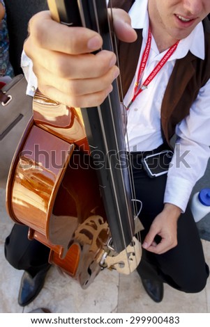 Musician playing the cello in the street. Musician recital giving abroad. Closeup of a cello.
