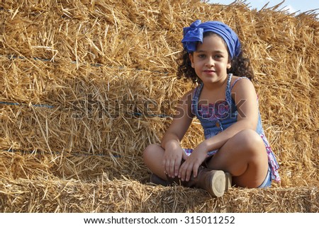 Little girl in the hay bale at the end of summer. Young girl in the field enjoying a summer afternoon.