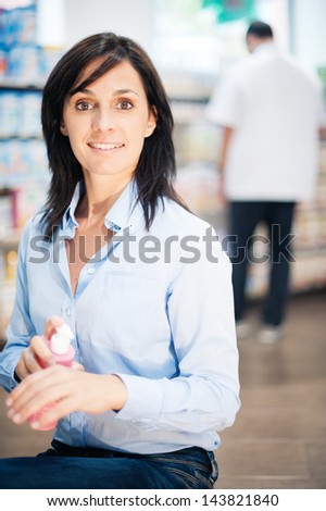 She is in the pharmacy. She is looking for some medicine. We can see the pharmacist in the background