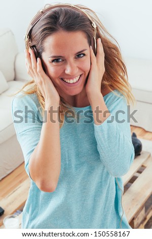 Happy girl dancing at home while listen music with headphones. She is in her home