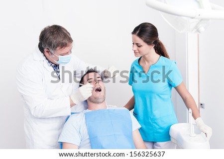 Dental surgery. There is a dentist, his assistant and the patient