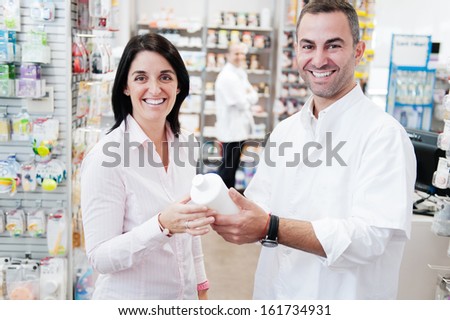 Smiling customer an pharmacist in a pharmacy. In the background we can see another pharmacist