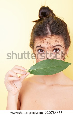 Brunette woman with a scrub applied and a sheet covering her face