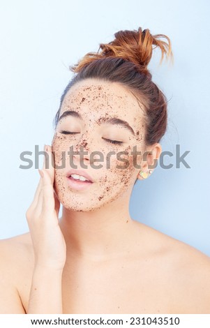 Red-haired woman with a scrub applied on her face
