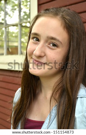 Portrait of female teen against red building with window smiling