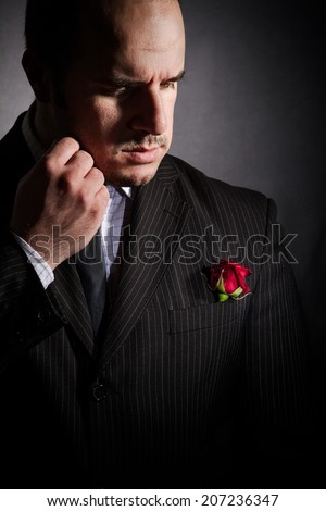 Portrait of man, godfather-like character. Studio shoot, black background.