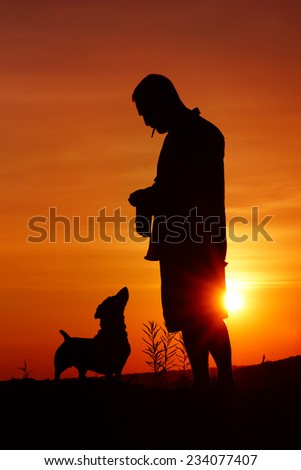 Smoking man and Daschund dog (Teckel) at orange sunset