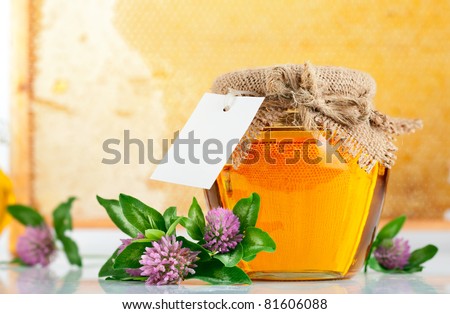 sweet honey in glass jars with flowers isolated on white background
