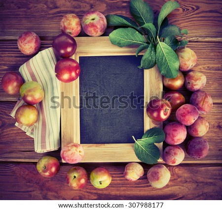 Board for text with fresh plums and green leaves