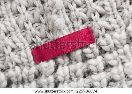 Blank red label on beige wool knitting as a background