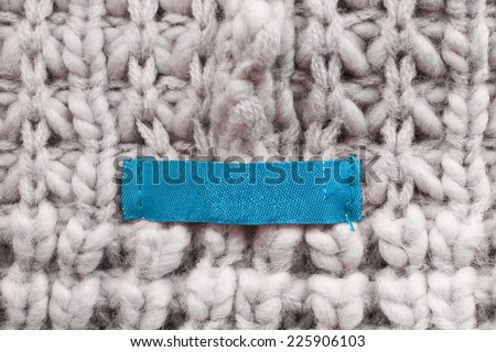 Blue blank label on beige wool knitting closeup