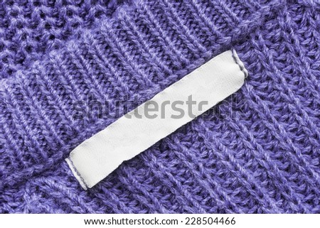 White blank label on purple knitted cloth as a background